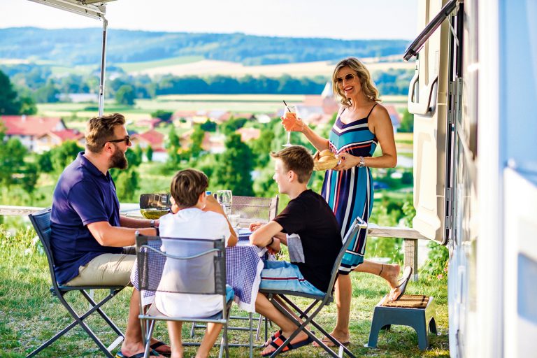 Eine Familie die zusammen campen geht in der Natur. Urlaub mit vier Personen und Wohnmobil.