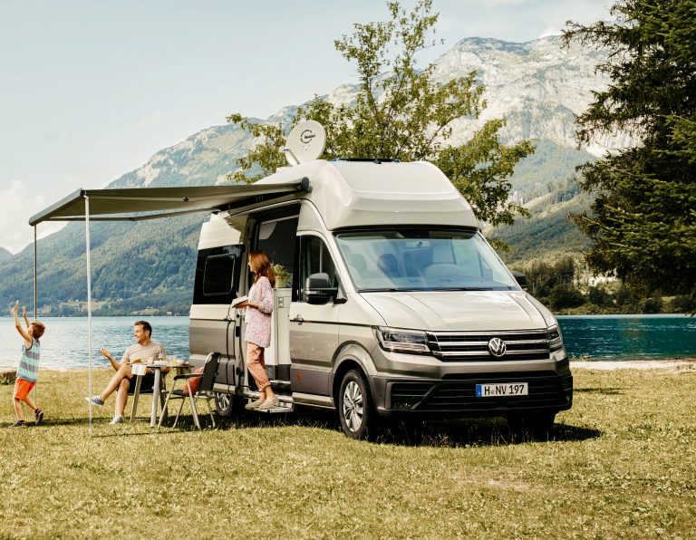 Glückliche Familie im VW Grand California 600 an einem See