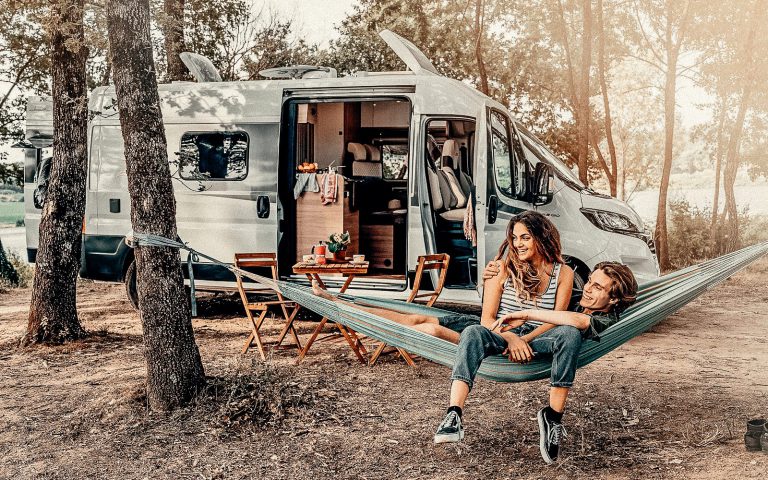 Pärchen in einer Hängematte vor einem Campervan