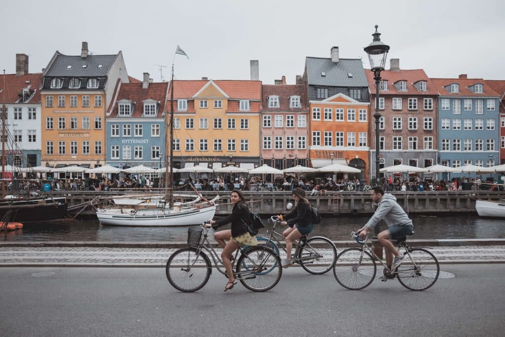 Drei Personen fahren Fahrrad vor bunten Häusern