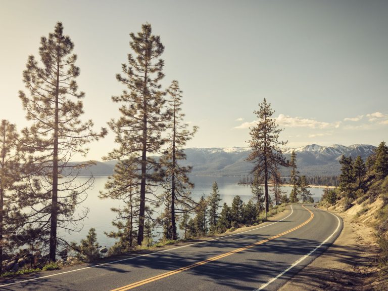 Wohin mit dem Wohnmobil im Mai - Blick auf eine Route mit Meer und Bäumen im Hintergrund