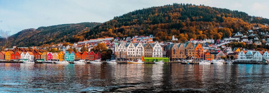 Skyline von Bergen mit Bunten Häusern und einem Herbstlichen Wald im Hintergrund