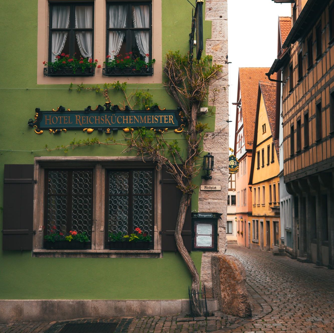 Grünes Haus mit Fensterläden und Fachwerkhäusern im Hintergund