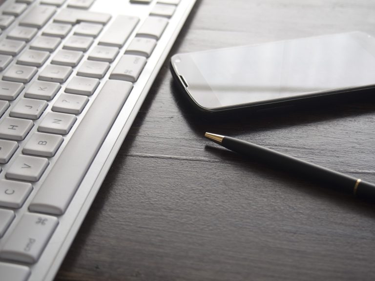 Tastatur, Handy und Stift auf einem Tisch