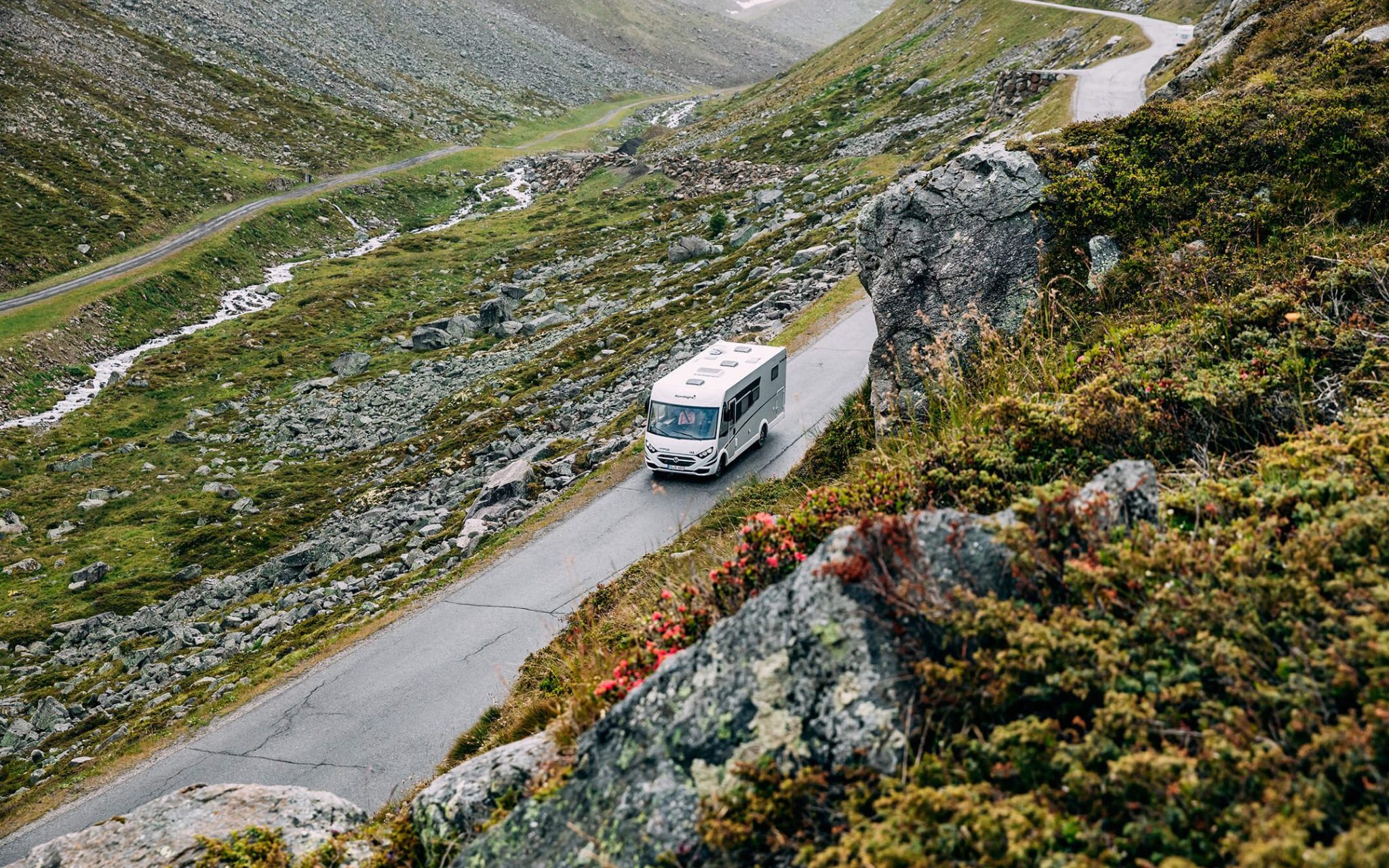 Wohnmobil fährt auf Straße in einer felsigen Umgebung