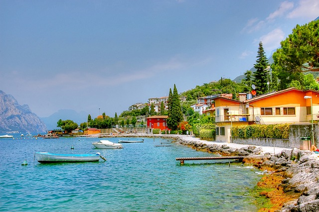 Glamping Italien - Blick auf den Gardasee mit Bäumen, Bergen und Häusern im Hintergrund.