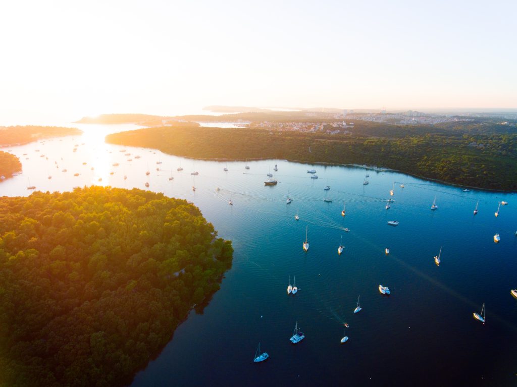 Glamping Kroatien - Sonnenuntergang über einer Wasserpassage mit vielen kleinen Booten