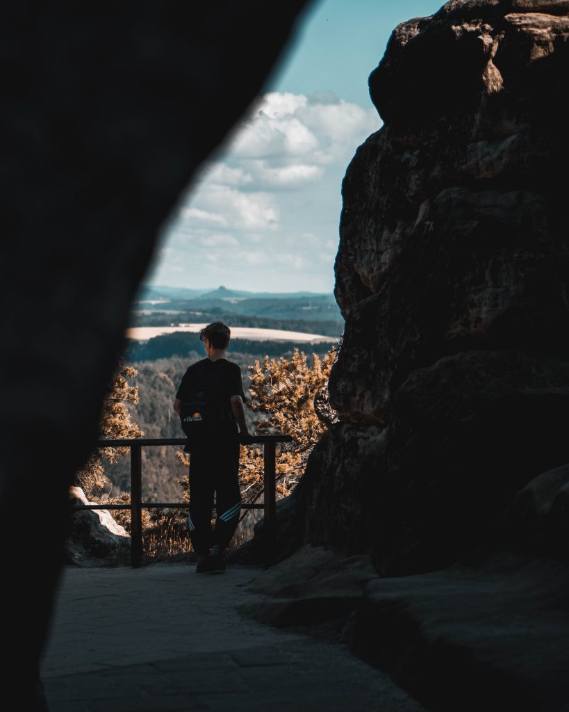 Camping Sächsische Schweiz - Mann steht in einem schmalen Gang und blickt auf die Landschaft 