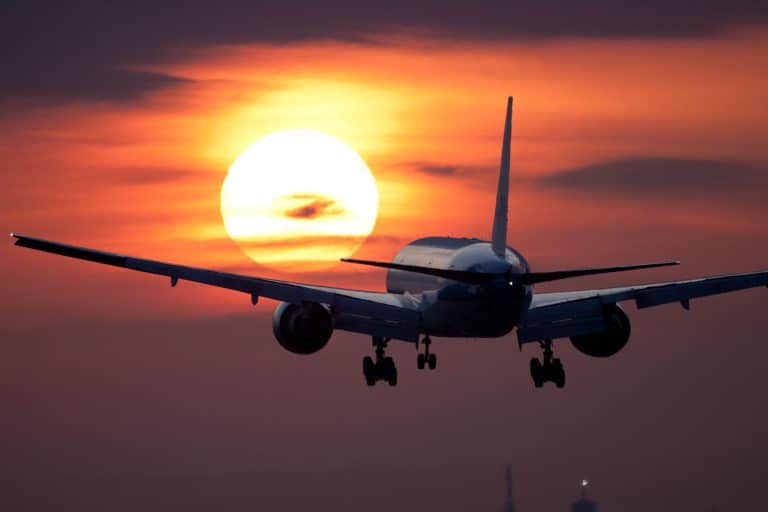 Campingurlaub mit dem Flugzeug - Flugzeug fliegt bei Sonnenuntergang