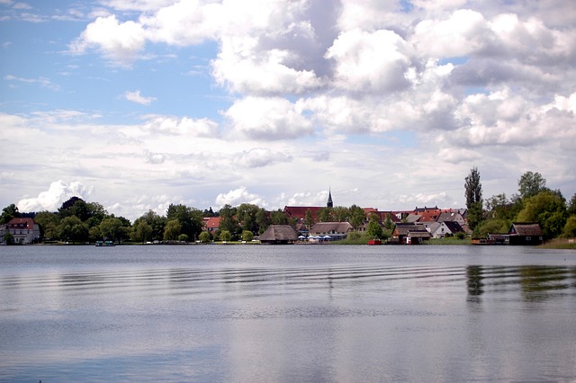 Camping Mecklenburgische Seenplatte - Blick auf die Müritz mit Häusern und Bäumen im Hintergrund.