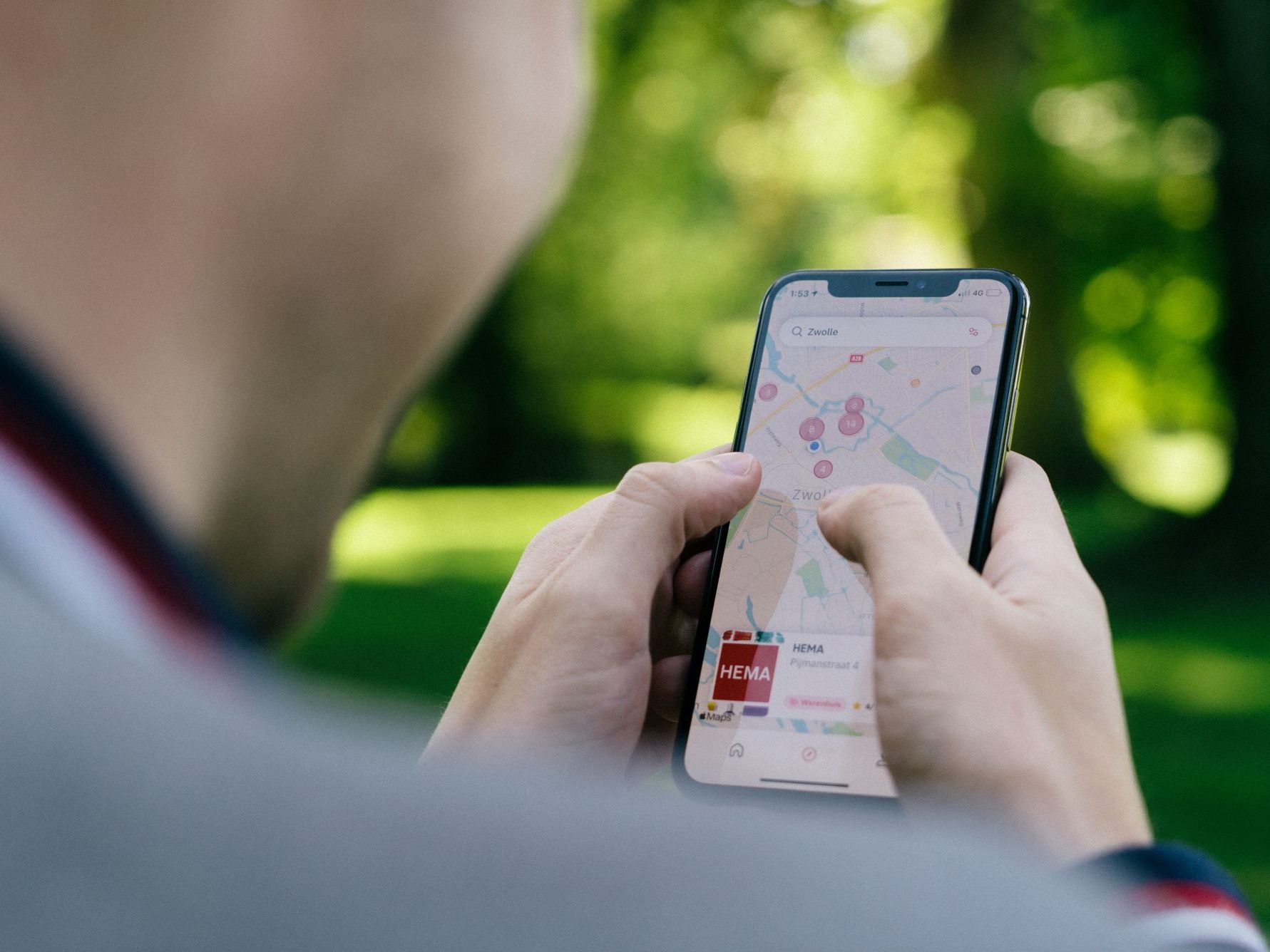 Mann schaut auf sein Handy. Auf dem Handy ist eine Karte geöffnet